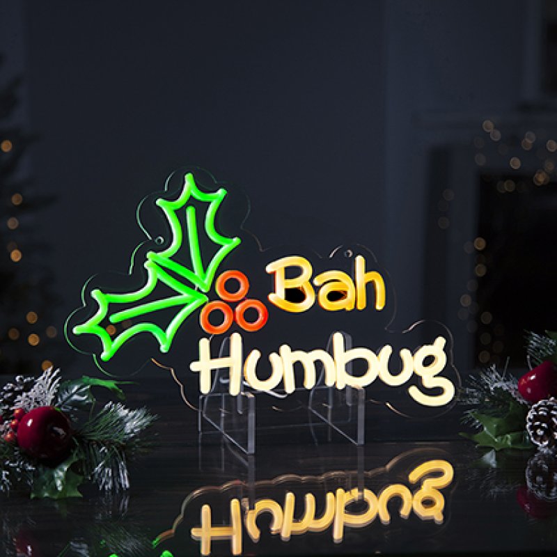 Neon sign with 'Bah Humbug' text and holly design on a dark background