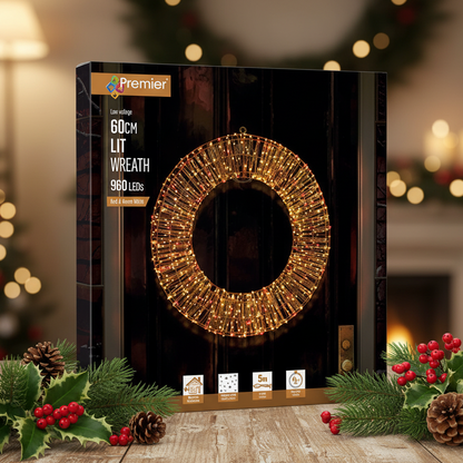 Premier 60cm lit wreath box packaging shown on a rustic wooden table with holiday greenery, pinecones, and warm bokeh lights in the background.