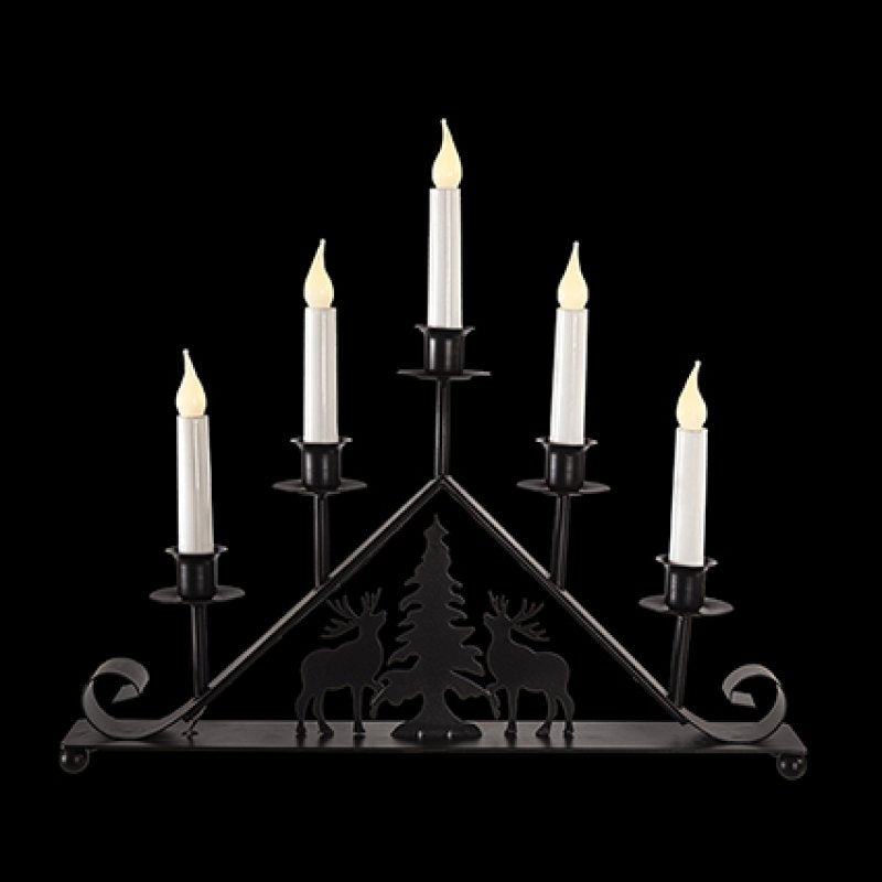 A black metal 5-light candelabra with a triangular frame, featuring silhouettes of deer and a Christmas tree on the front, holding five white faux candles with lit flame tips, set against a solid black background.
