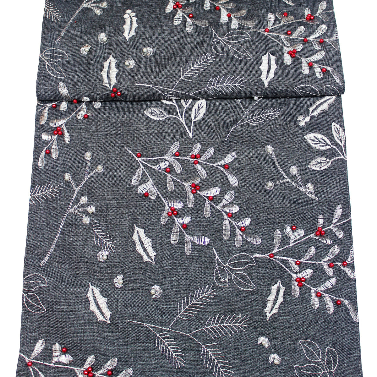 A folded dark grey fabric table runner featuring a silver embroidered botanical pattern of leaves, pine branches, and small red berry accents.