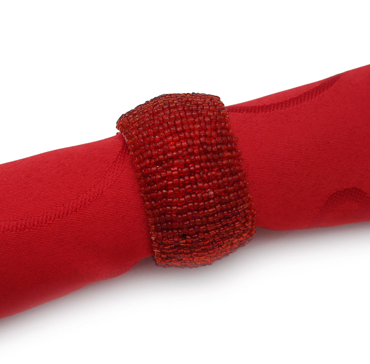 A close-up of a red fabric napkin wrapped with a glass, beaded red napkin ring set against a plain white background.