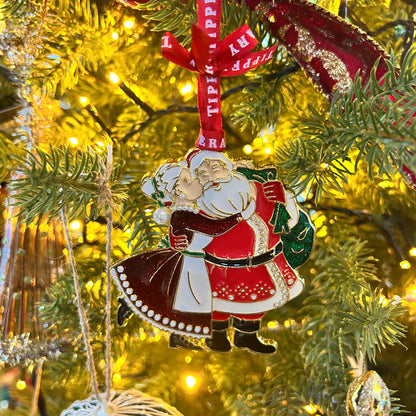 Decorative Christmas ornament of a couple hugging on a tree with lights in the background