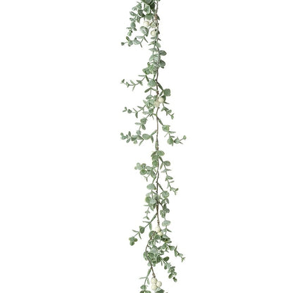 A garland of green leaves and white berries, fanned out to create a flat lay appearance.