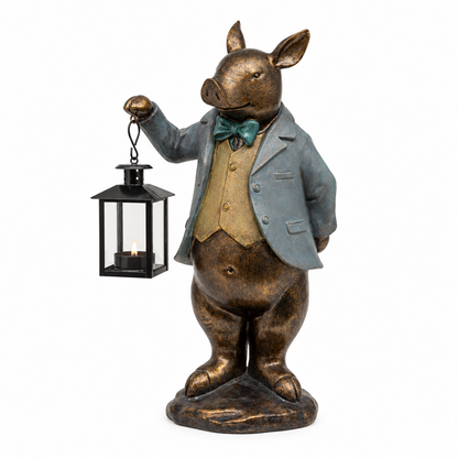 A decorative pig figurine dressed in a gray blazer, gold vest, and teal bow tie, holding a black lantern with a lit candle, shown on a plain white background.