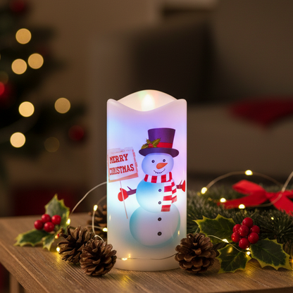 A cylindrical LED candle-style lamp with a glowing white body and a printed snowman design holding a 'MERRY CHRISTMAS' sign. The lamp is shown on a plain white background with colorful light leaks around the edges.