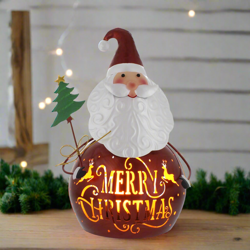 A brown metal lantern with a Christmas theme, featuring Santa Claus, reindeer, and a festive message 'Merry Christmas' illuminated in the dark.
