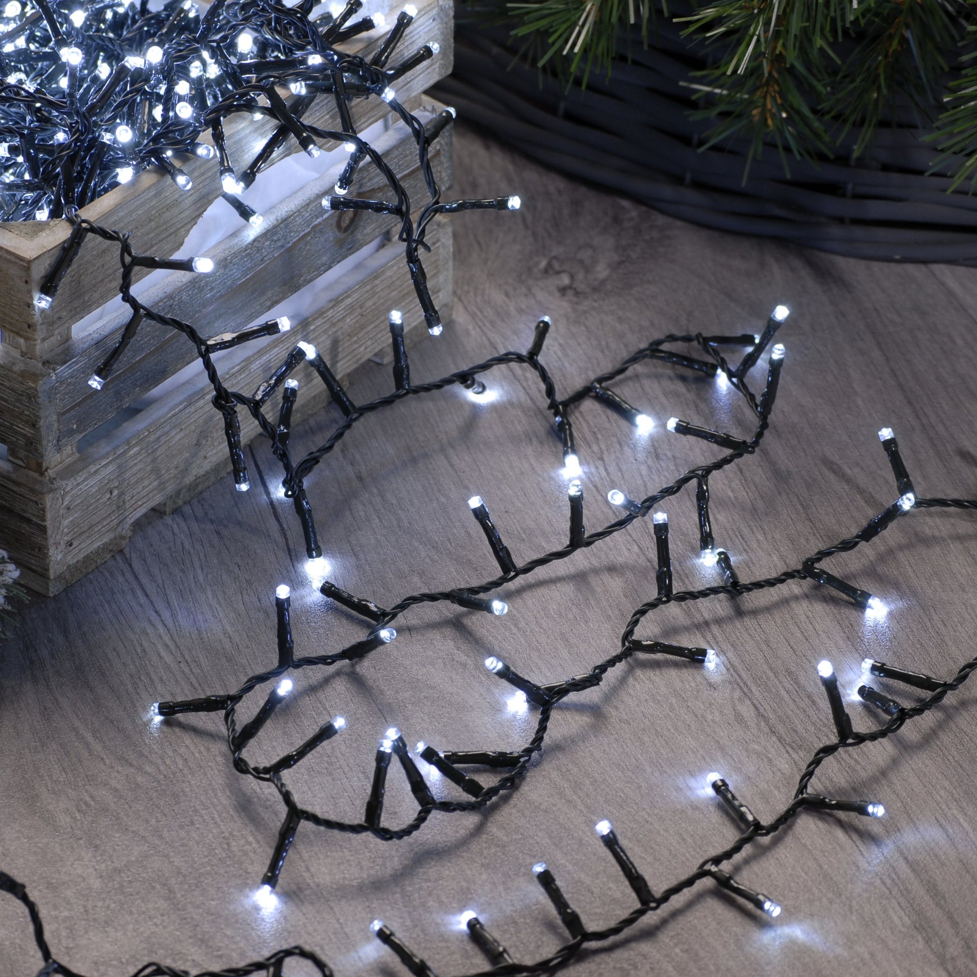 A string of white firefly LED Christmas lights spread out on a wooden surface, creating a festive atmosphere.