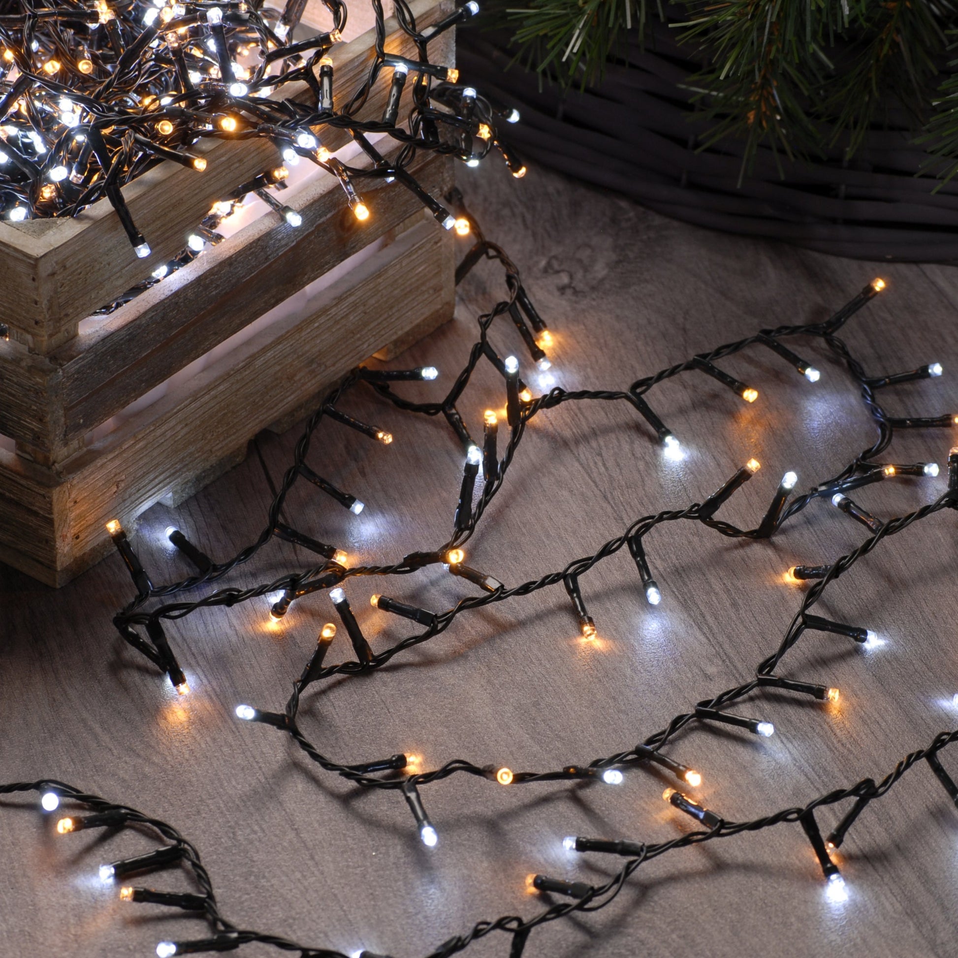 A set of Festive 300 White and Warm White Firefly Christmas Lights laid out on the floor, showing both warm white and white LED bulbs.