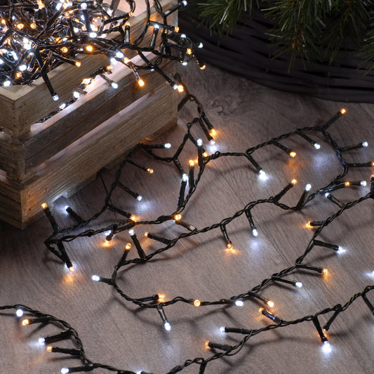 A set of Festive 300 White and Warm White Firefly Christmas Lights laid out on the floor, showing both warm white and white LED bulbs.