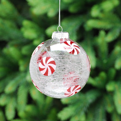 A clear crackle effect glass bauble with a candy cane design, featuring red and white stripes, displayed on a Christmas tree with green leaves in the background.