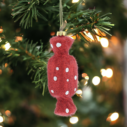 A red glittery hanging decoration with a textured surface and gold hanging string, displayed on a Christmas tree.