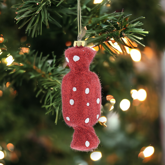 A red glittery hanging decoration with a textured surface and gold hanging string, displayed on a Christmas tree.