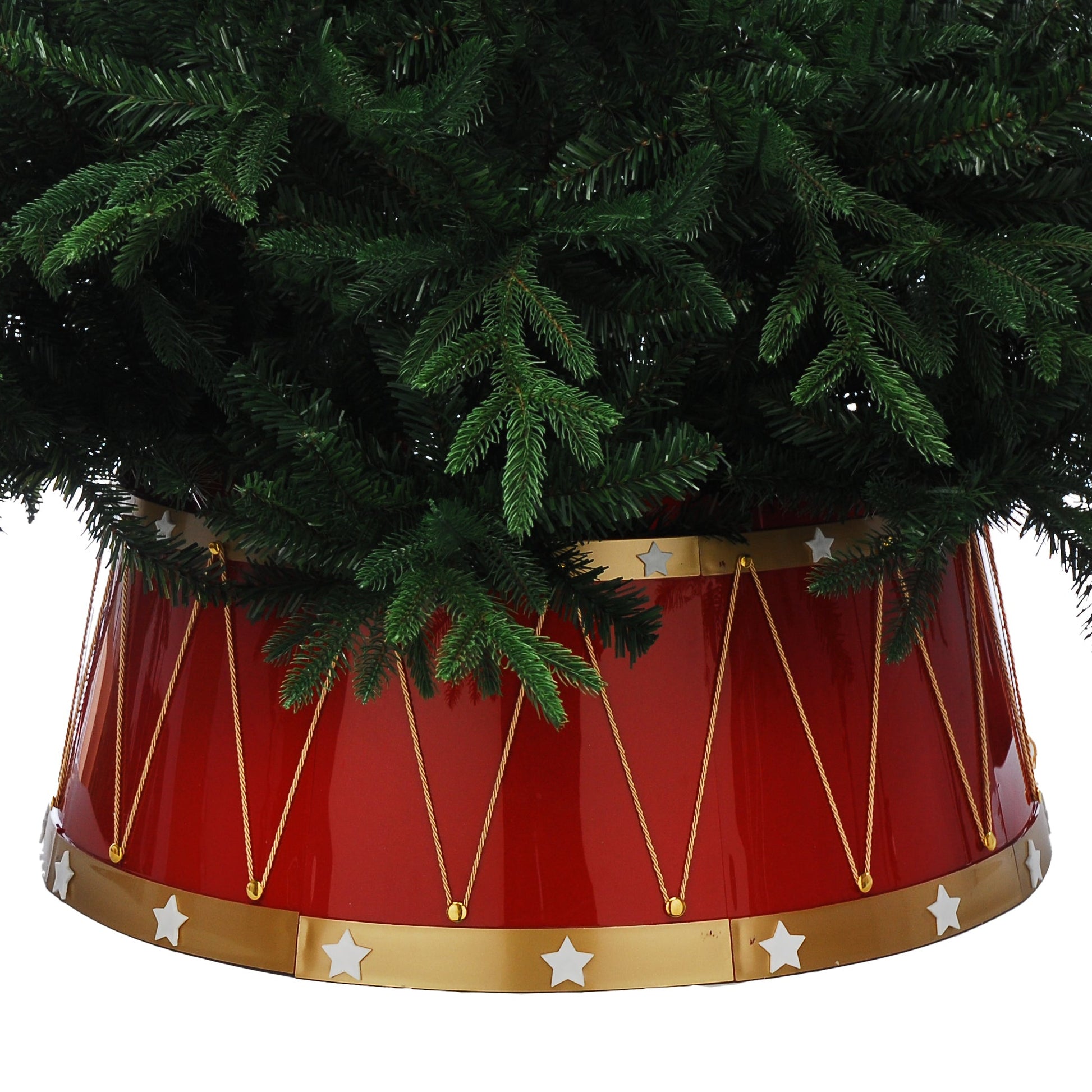 A red drum-shaped artificial Christmas tree skirt with gold trim and white stars, holding a green artificial tree against a white background.