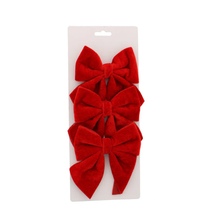 Three red velvet bows stacked vertically on a white cardboard hanger display, photographed against a solid white background.