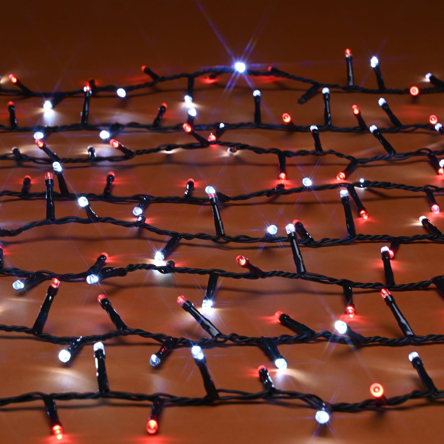 Red, white LED holiday string lights draped across a warm brown surface, glowing with bright starburst effects.