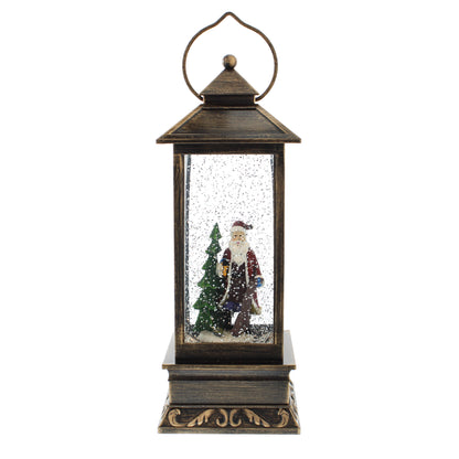 A rustic dark bronze lantern Christmas decoration featuring a Santa Claus figurine inside a clear glass snow globe with falling snow and a small green tree, set against a plain white background.