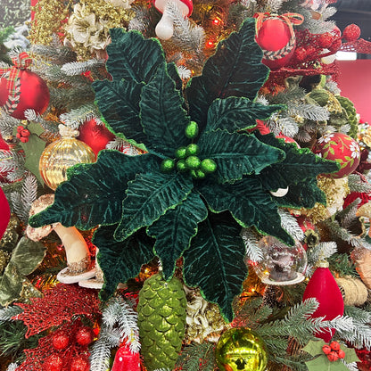 A dark green Christmas poinsettia stem with glitter, placed in a festive Christmas tree with red and gold decorations.