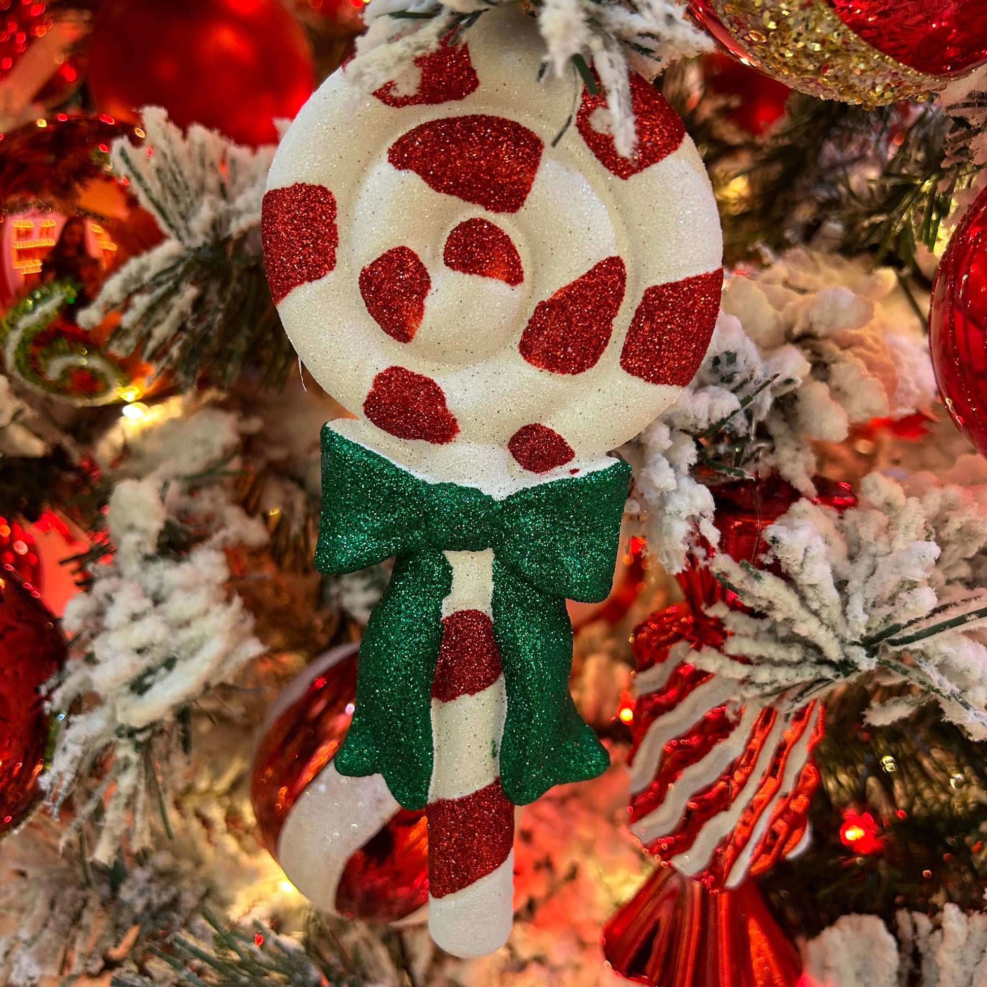A candy cane lolly with a green bow hanging as a decoration.