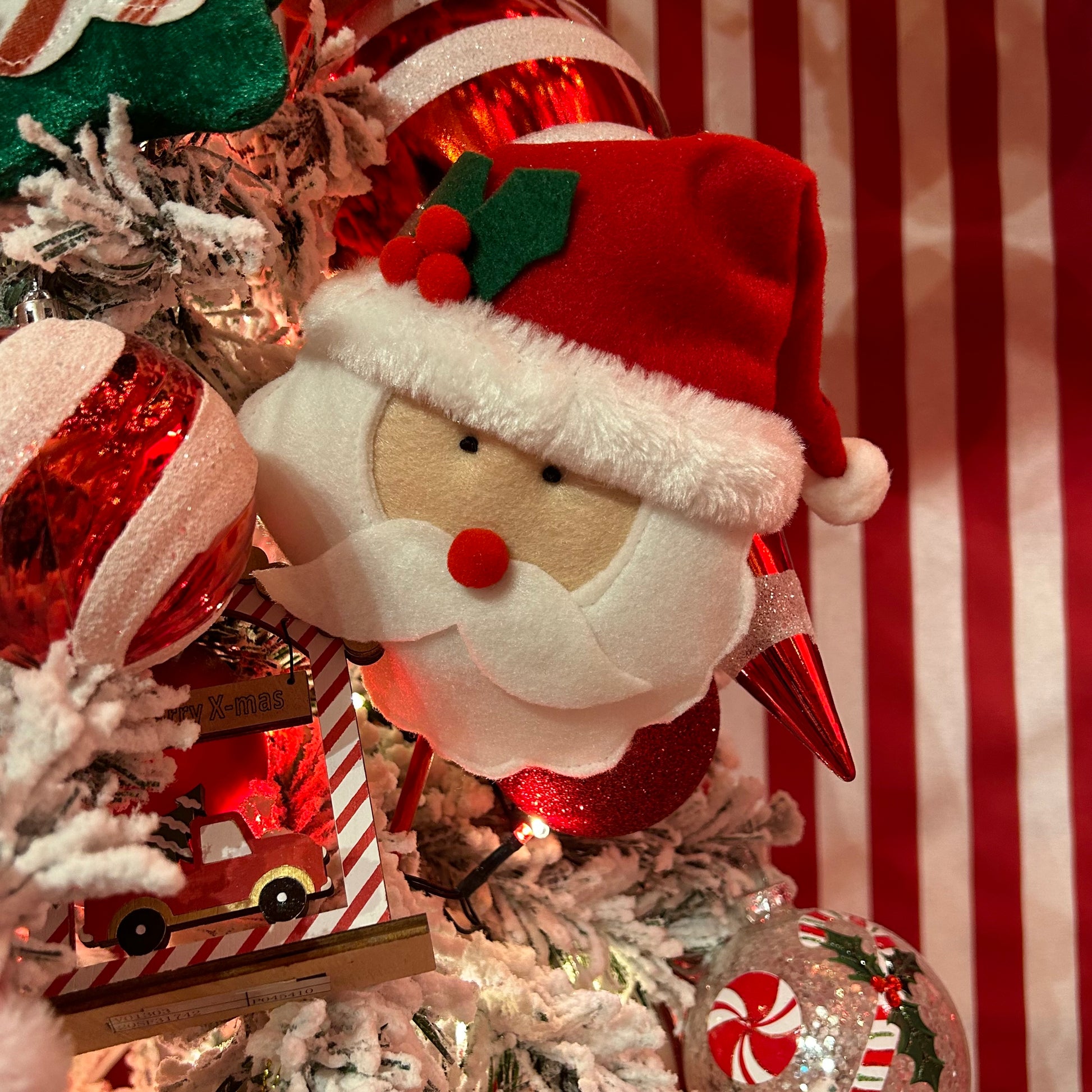 A decorative Santa Head Christmas Tree Pick with a striped background, featuring a fabric representation of Santa's head with a red hat and white beard.