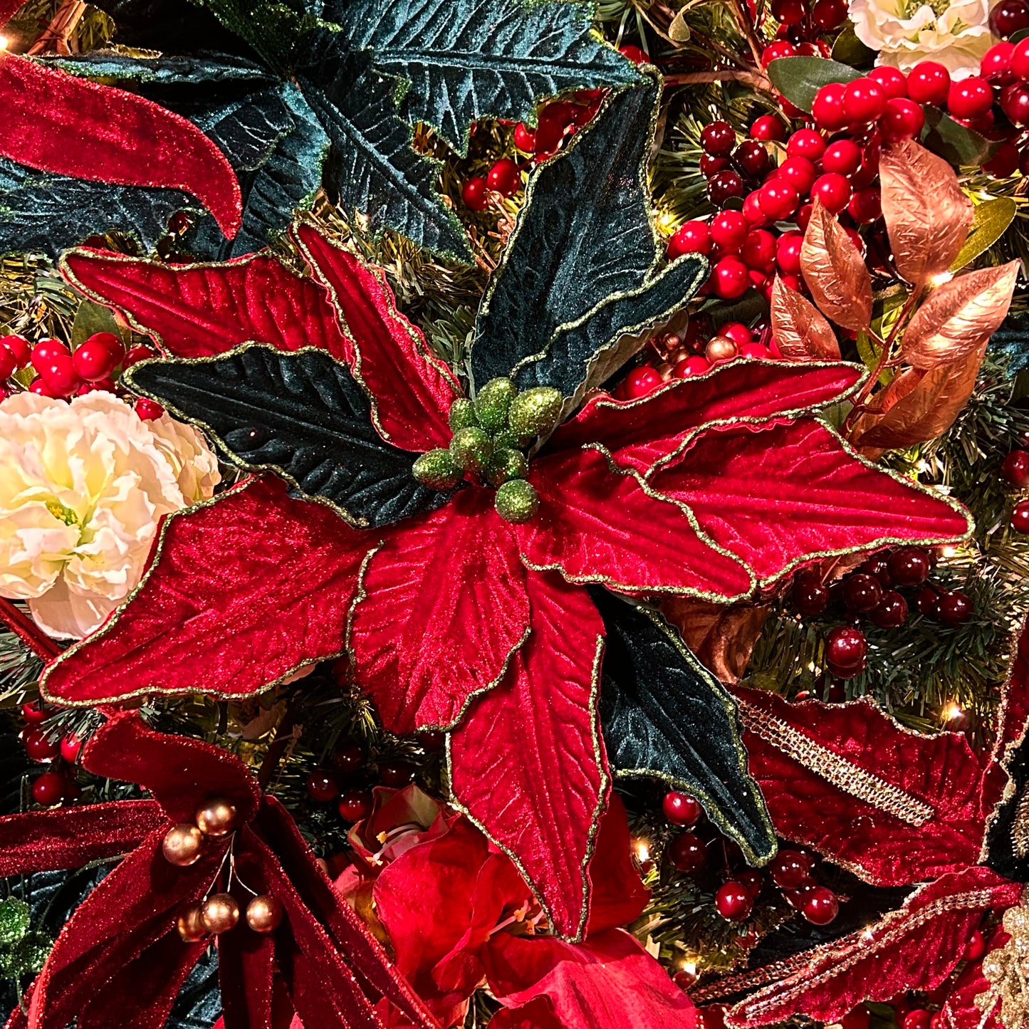 A close-up of a red and green poinsettia stem with artificial leaves, designed for use in holiday decorations.