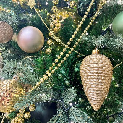 A close-up of a golden bead garland adorning a Christmas tree, showcasing its shiny beads and ornate tassel.