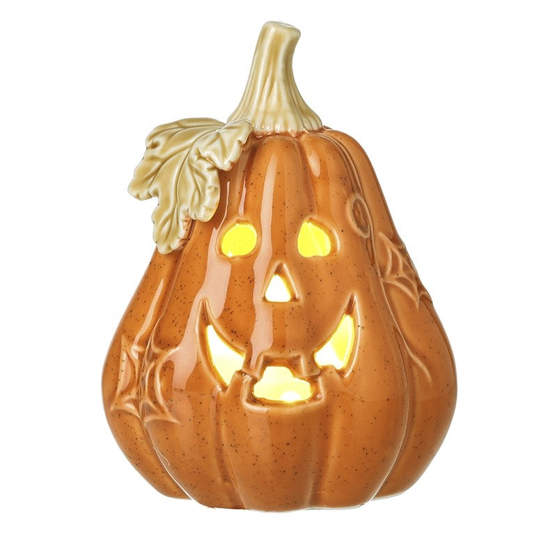 A ceramic jack-o'-lantern pumpkin decoration with a warm orange-brown speckled glaze, carved facial features, spiderweb details, and a light beige stem and leaf, shown against a plain white background.