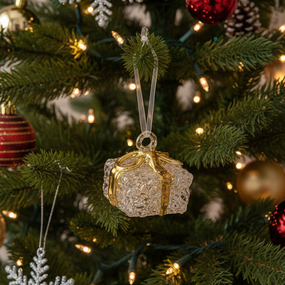 Four small gift box ornaments hanging on a white background, each with a textured clear body and a ribbon in red, gold, green, or silver.