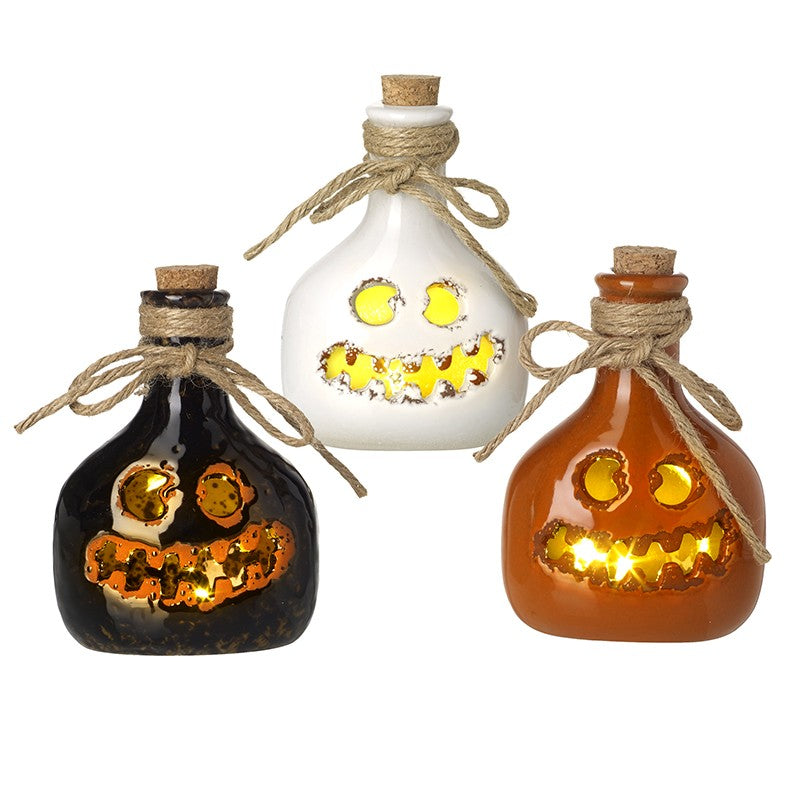 Three decorative bottles with jack-o'-lantern faces on a white background