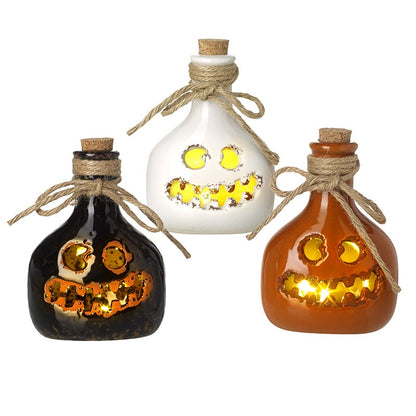 Three decorative bottles with jack-o'-lantern faces on a white background