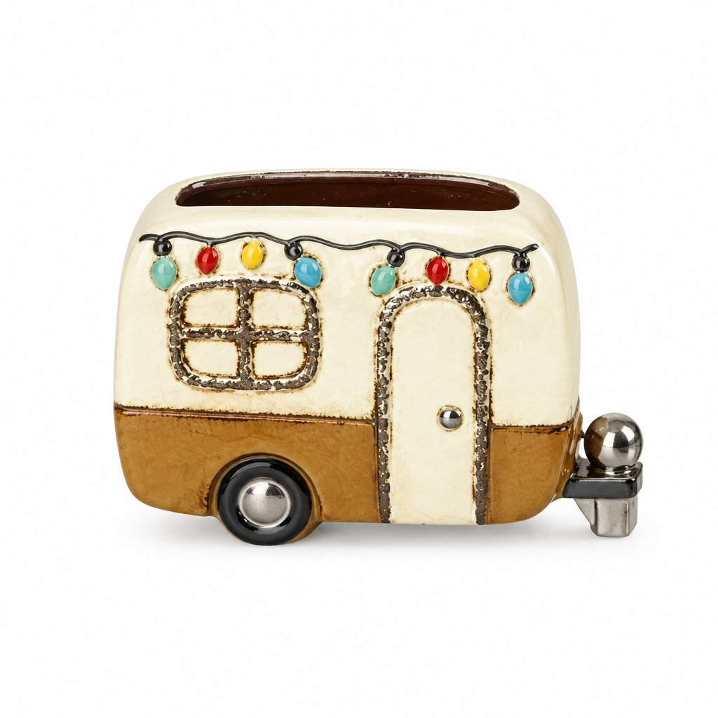 A novelty ceramic caravan shaped like a retro travel trailer, featuring an off-white body, tan lower section, and small colourful decorative accents, shown on a plain white background.