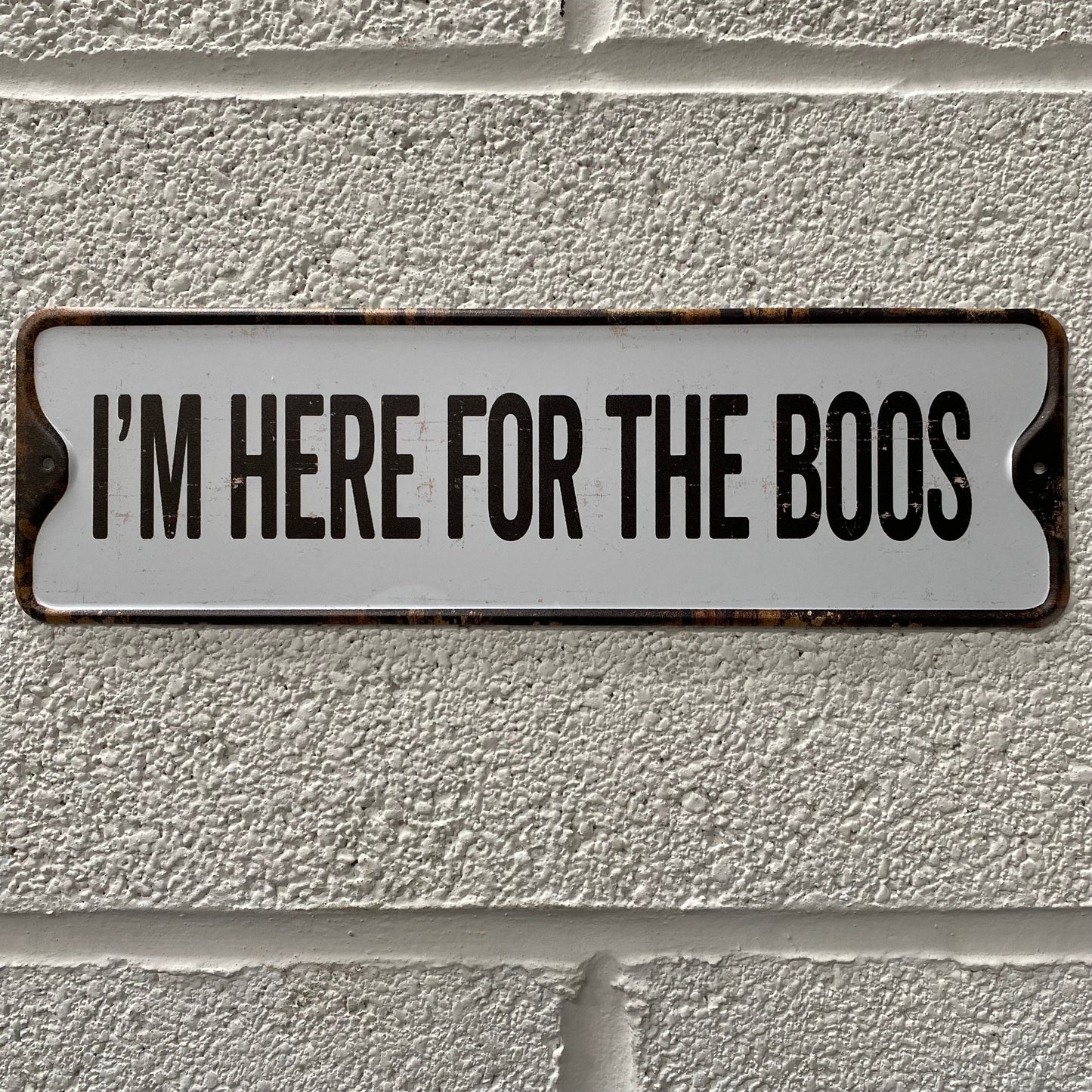 Halloween sign, that reads I'm here for the boos, placed on a white brick wall
