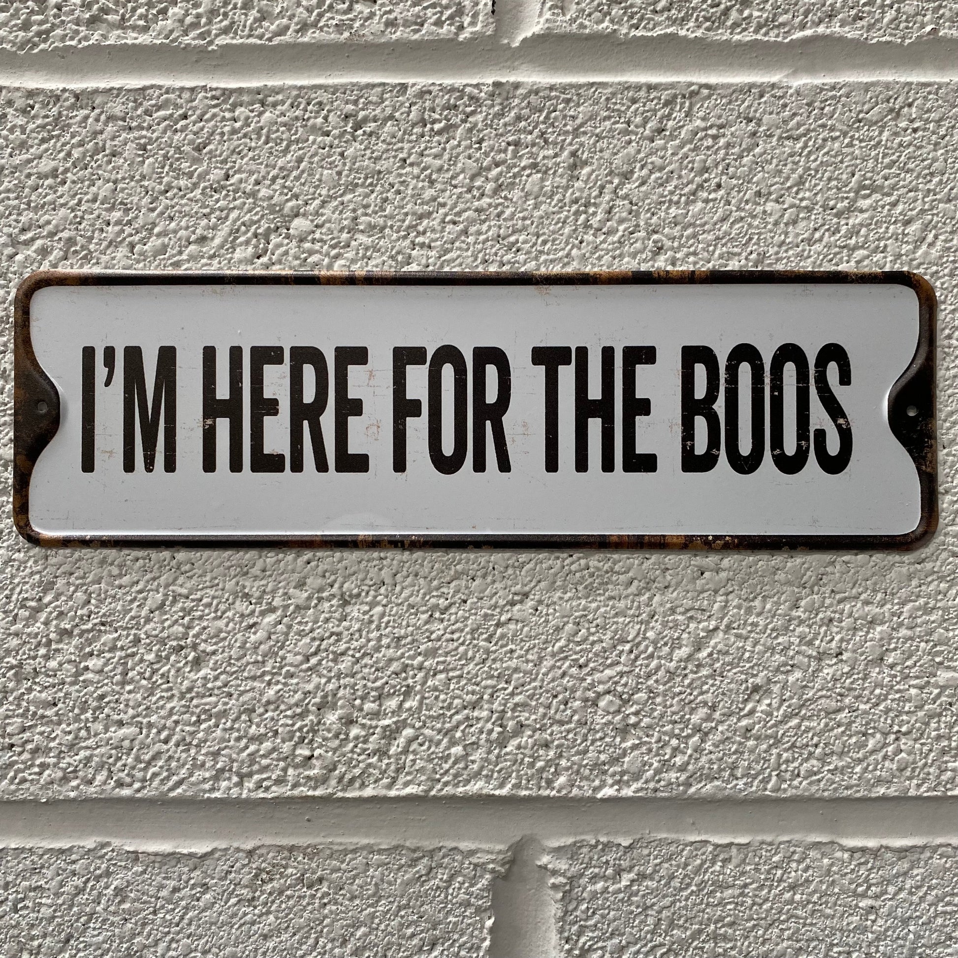 Halloween sign, that reads I'm here for the boos, placed on a white brick wall