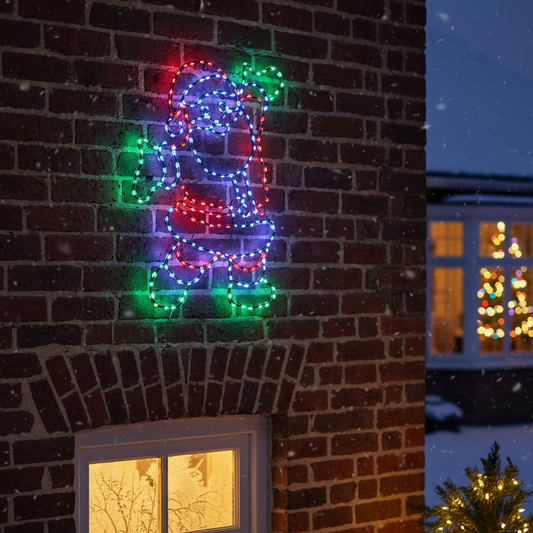 Colorful LED dog-shaped light decoration on a brick wall with a snowy night scene.