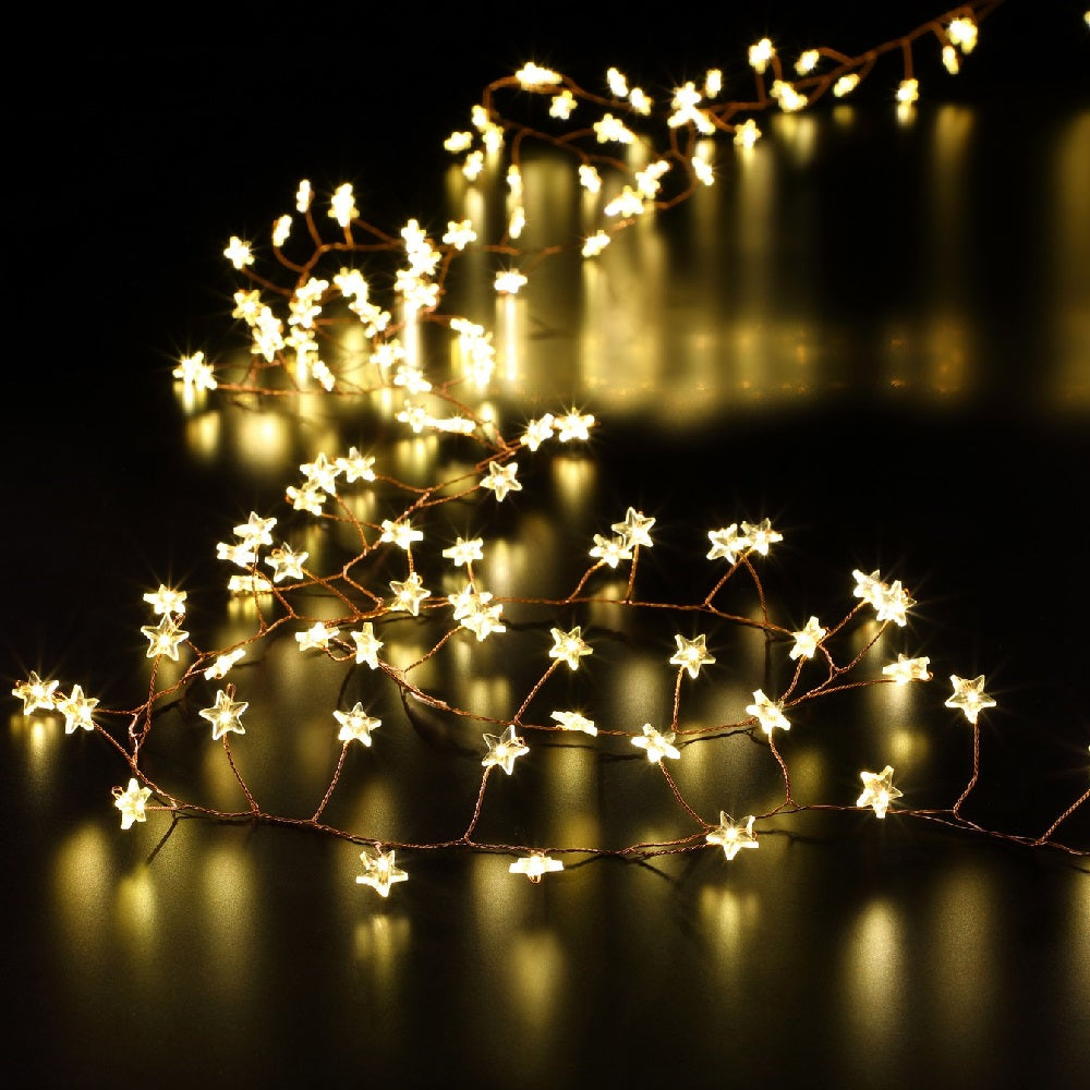 A string of warm white LED Christmas star garland lights placed on a surface, with a blurred background.