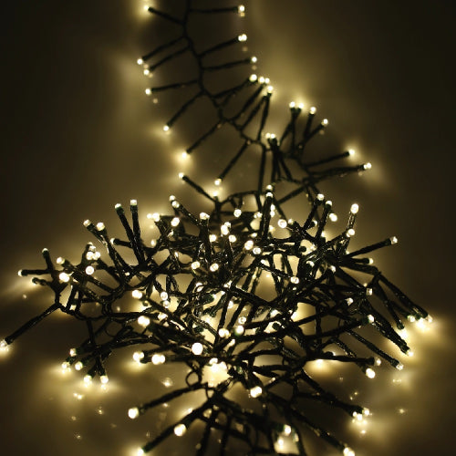 A close-up of warm white Christmas lights with a green cable, showing the lights glowing in a dark setting.
