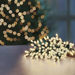 Battery operated string lights with warm white LED bulbs, set against a blurred background of Christmas tree lights.