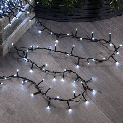 A set of festive sparkle Christmas lights arranged on a wooden floor, designed to illuminate a Christmas tree, with a focus on the lights' glow and not the lights themselves.