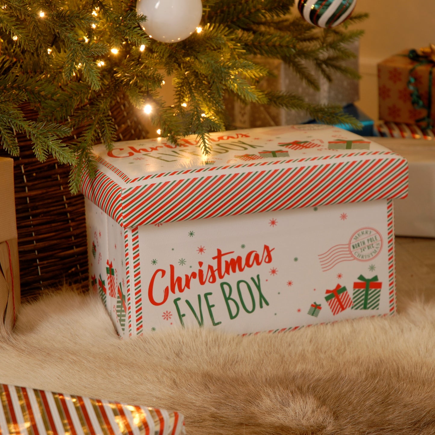 A foldable Christmas Eve box placed under a Christmas tree, decorated with festive patterns and text.