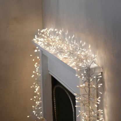 Christmas lights with white clear cable wrapped around a fireplace mantle, providing a bright and festive illumination.