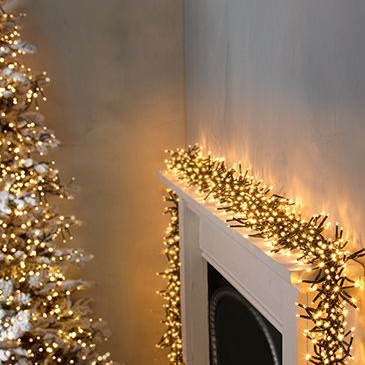 Christmas lights with a cluster of warm white LEDs extending across a room, with a Christmas tree and decorations visible in the background.