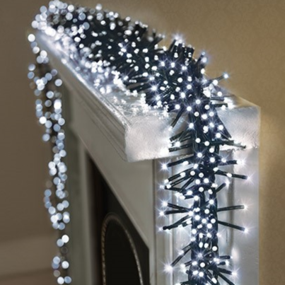 A close-up of white LED Christmas lights arranged in a cluster on a mantelpiece, showcasing the bright LED lights against a dark cable.